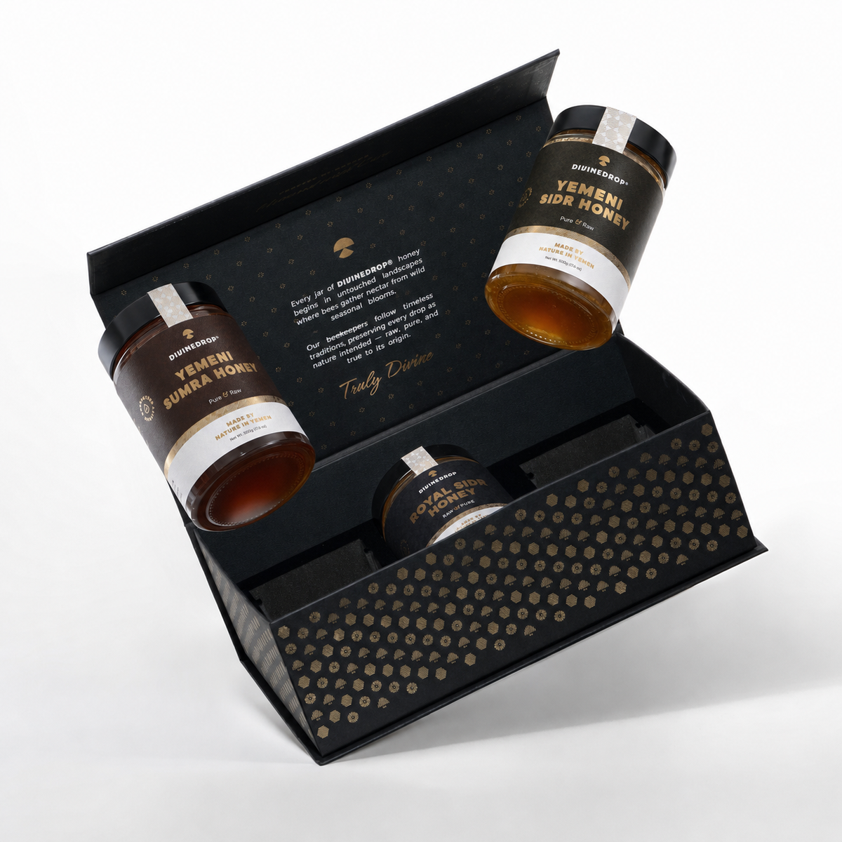 A premium honey gift set from True Elixir, featuring three glass jars of Yemshi Suma Honey, Yemshi Sidr Honey, and a smaller jar, presented in an open black gift box with gold patterns on a white background.