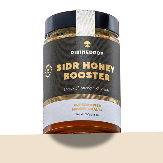 A jar of DIVINEDROP Sidr Honey Booster on a white background with a beige surface at the bottom. The jar has a black lid, a dark brown label with gold and white text, and a white seal on top.